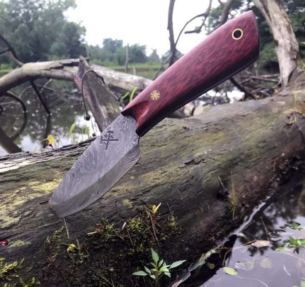 A knife is laying on the ground near some water.