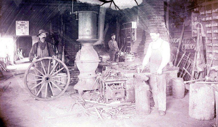 A man standing in front of an old fashioned stove.