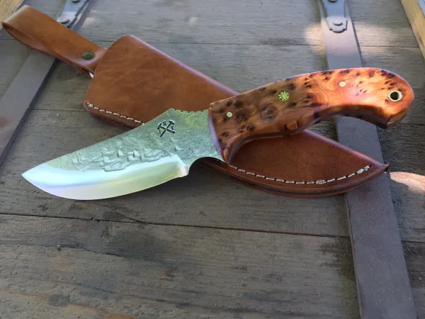 A knife laying on top of a wooden table.