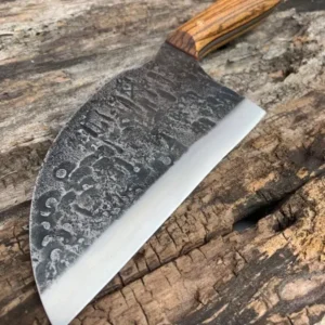 A large knife with an engraved blade on top of a wooden table.