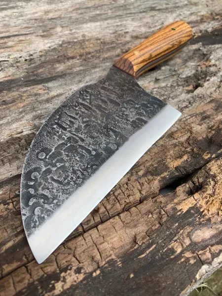 A large knife with an engraved blade on top of a wooden table.