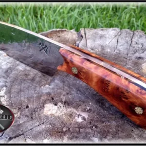 A knife that is sitting on top of a tree stump.