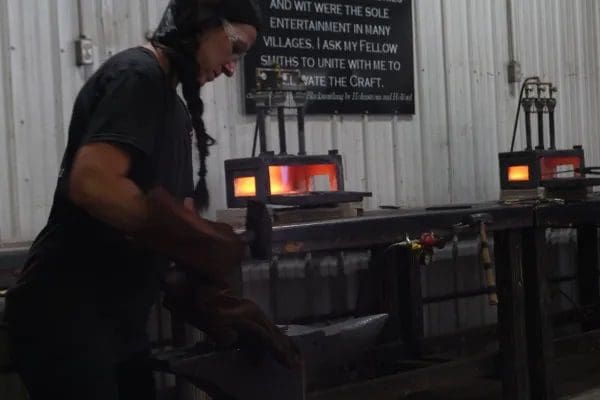 A person in black shirt working on metal object.