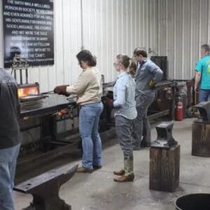 A group of people standing around in front of some metal.