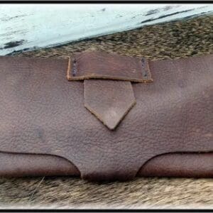 A brown leather purse sitting on top of the ground.