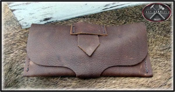 A brown leather purse sitting on top of the ground.