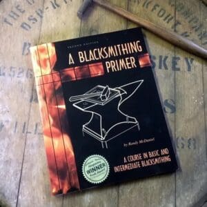 A book on blacksmithing is laying on top of a table.