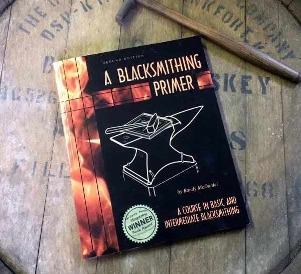 A book on blacksmithing is laying on top of a table.