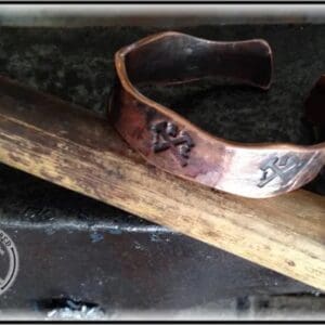 A close up of a metal bracelet on top of a wooden stick.