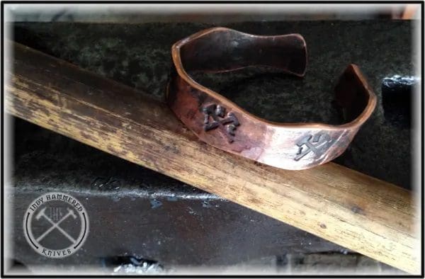 A close up of a metal bracelet on top of a wooden stick.