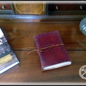 A book is sitting on the table next to a glass.