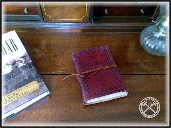 A book is sitting on the table next to a glass.