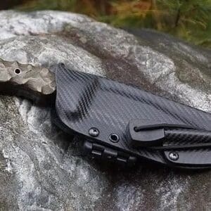 A black knife laying on top of a rock.