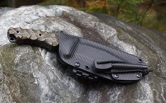 A black knife laying on top of a rock.