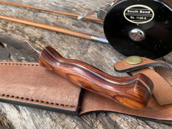 A wooden handle is sitting on top of a brown wallet.