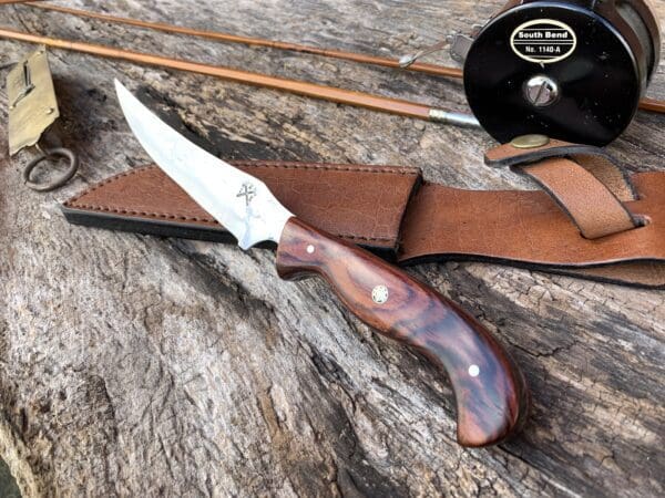 A knife and some leather sheath on top of a table.