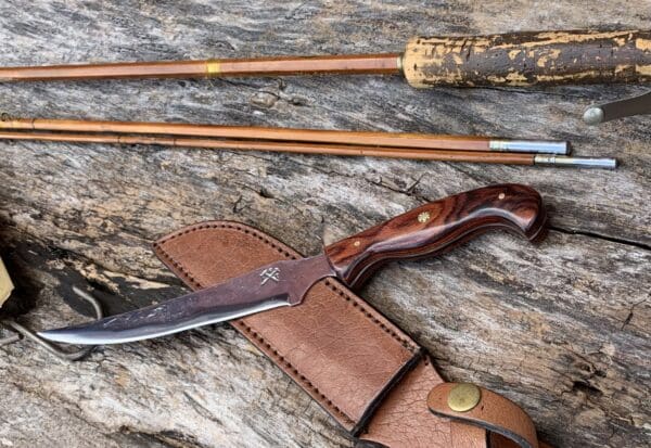 A knife and some arrows on top of a wooden table.